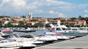 A marina with multiple boats docked, a church in the background, and a town with red-roofed buildings. - Hilde Blue by Interhome (Medulin)
