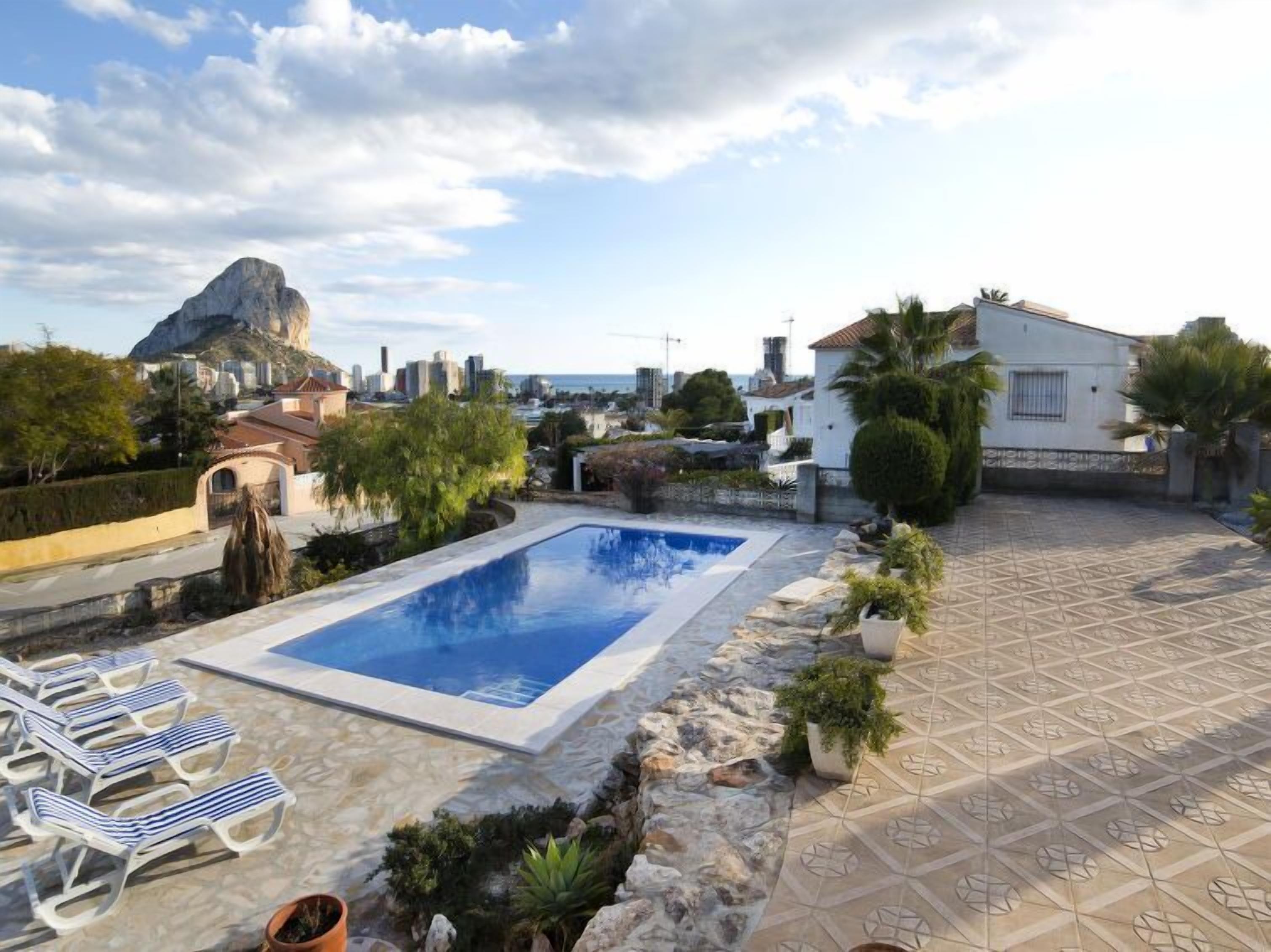 Uma área de piscina no terraço com espreguiçadeiras, um pequeno jardim e vista para a paisagem urbana.