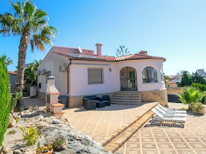 A two-story house with a tiled patio, outdoor seating, and a satellite dish.