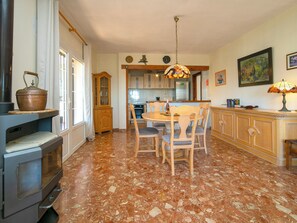 A kitchen with a stove, dining table, chairs, and a hanging light fixture.