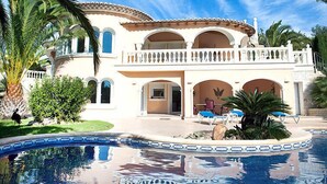 A large, two-story house with a swimming pool, surrounded by palm trees and a clear blue sky. - Vacation home Calina by Interhome (Benissa)