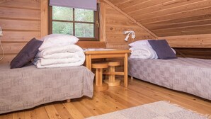Une chambre mansardée chaleureuse, avec deux lits, une petite table et une fenêtre.