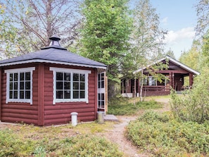 A cabin with a chimney, a window with a white frame, and a door.