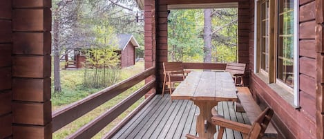 Un patio in legno con tavolo e panche, affacciato su una zona boschiva.