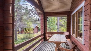 Une terrasse en bois, agrémentée d’une table de pique-nique et de bancs, entourée d’une rambarde en bois, et offrant une vue sur une zone boisée.