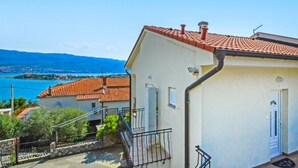 A coastal building with a red-tiled roof, a small balcony, and a view of the sea and mountains in the background. - Vacation home Ivan by Interhome (Krk/Šilo)