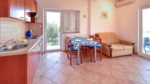A compact kitchen with a dining area, a sofa, and a balcony. - Vacation home Ivan by Interhome (Krk/Šilo)