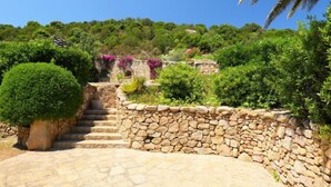 A stone pathway leading to a stone wall with a small staircase. - Paradiso by Interhome (Porto Cervo)