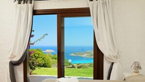 A bedroom with a bed, a view of the sea, and a window with curtains. - Paradiso by Interhome (Porto Cervo)