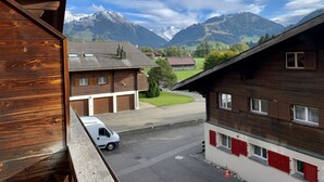 Un bâtiment en bois offrant une vue sur des montagnes enneigées, avec un fourgon blanc garé au premier plan.