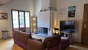 Un salon chaleureux avec une cheminée, un canapé, un téléviseur et une affiche accrochée au mur.