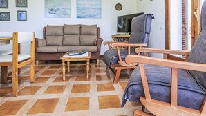 Un salon comprenant un canapé, des fauteuils, une table basse et un téléviseur.