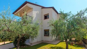 Une maison à deux étages, dotée d’un toit plat, d’un petit porche et d’une pelouse bien entretenue.