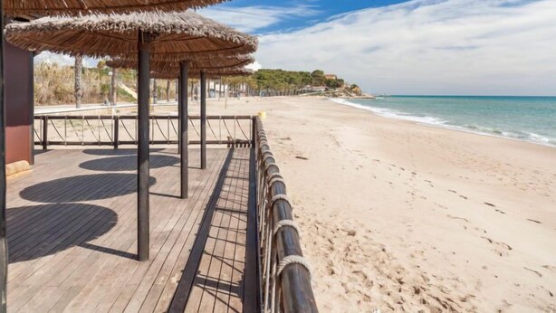 Une promenade en bord de mer agrémentée de parasols en chaume et d’une terrasse en bois.