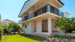 Une maison à deux étages avec un balcon, un toit plat et un ciel dégagé.