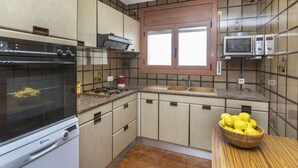 Une cuisine équipée d’une cuisinière, d’un four, d’un four à micro-ondes et d’une fenêtre.