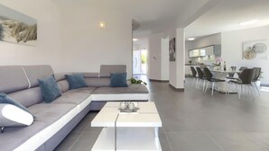 Een moderne woonkamer met een modulaire bank, een salontafel en een eethoek met stoelen en een tafel.
