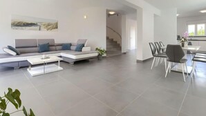 Een moderne woonkamer met een hoekbank, een salontafel en een eethoek met stoelen en een tafel.