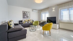 A modern living room with a grey sofa, yellow armchair, and a flat-screen TV.