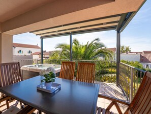 A balcony with a table, chairs, a hot tub, and a potted plant. - Apartment Damir by Interhome (Crikvenica)