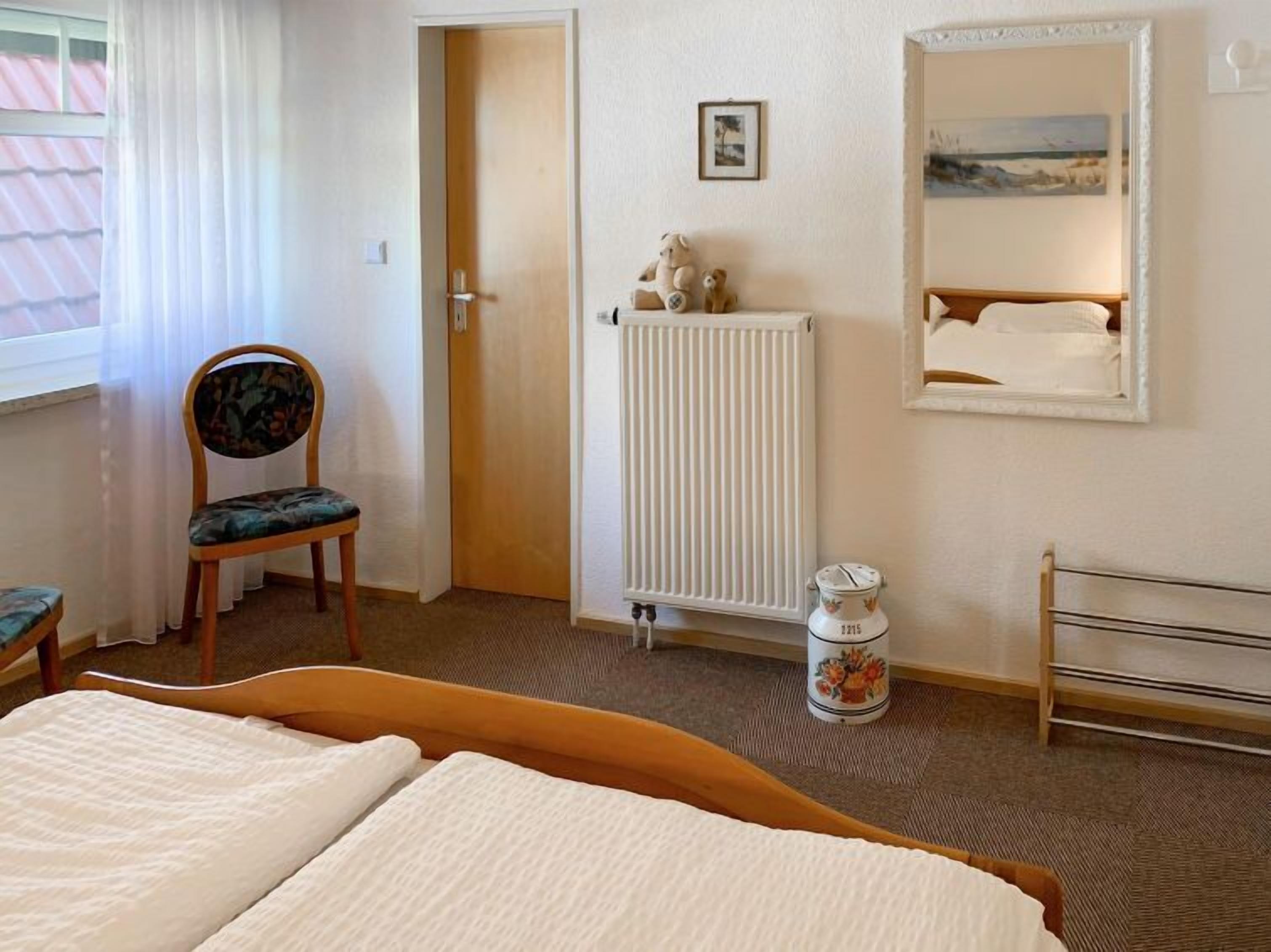 Ein Hotelzimmer mit einem Bett, einem Sessel, einem Heizkörper, einem kleinen Tisch mit einer Dekoration und einem gerahmten Bild an der Wand.