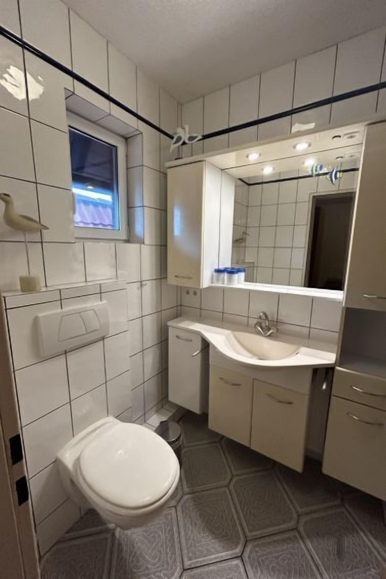 Ein modernes Badezimmer mit Toilette, Waschbecken und Spiegel.