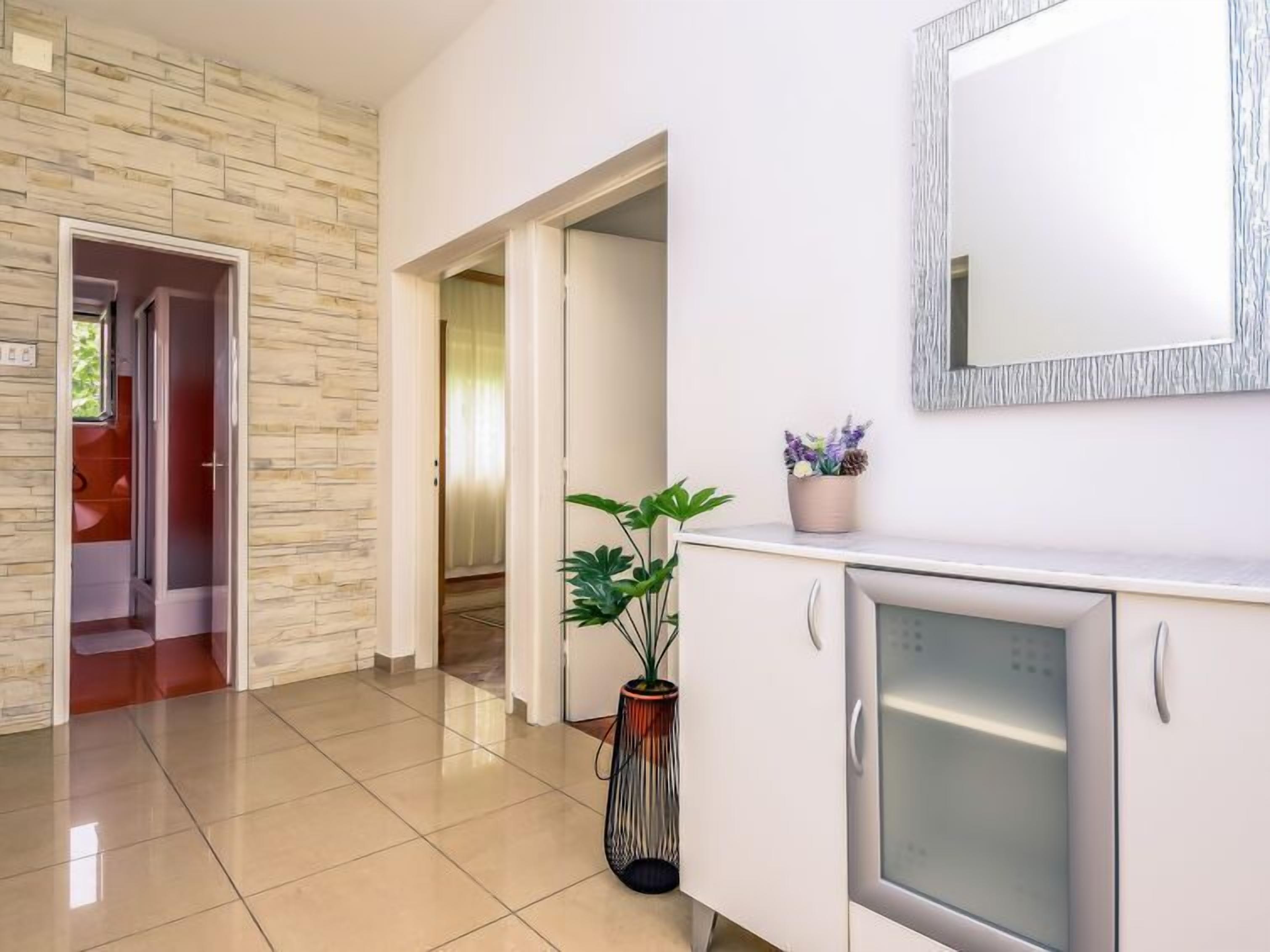A modern hotel lobby with a stone wall, a potted plant, and a refrigerator.