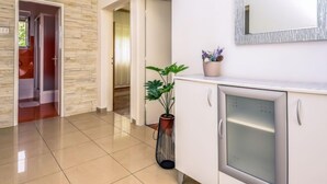 Un hall d’hôtel moderne avec un mur en pierre, une plante en pot et un réfrigérateur.