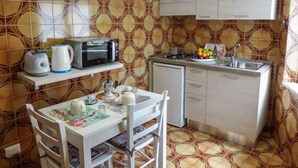 Una cocina compacta con microondas, tostadora y lavamanos.