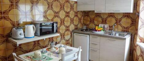 Een koelkast, een microgolfoven, kookgerei, borden en bestek