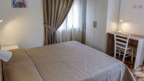 Un dormitorio con cama, escritorio, silla y armario.