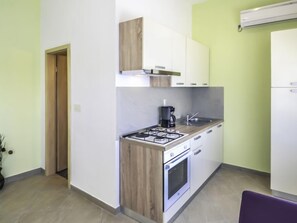 A compact kitchen with a gas stove, oven, and a coffee maker.