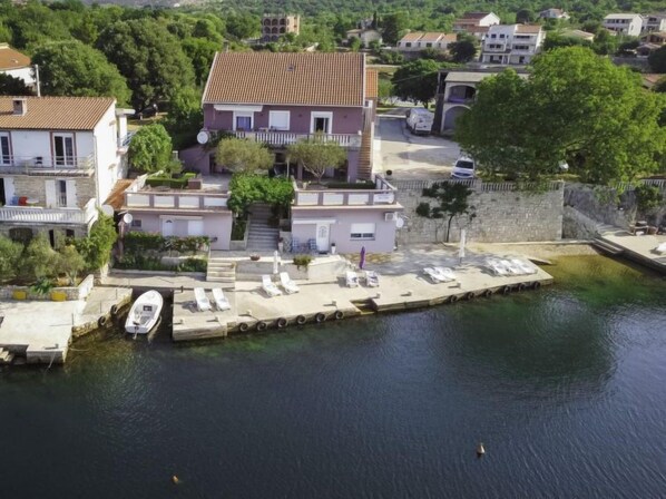 A waterfront property with a dock, lounge chairs, and a boat.