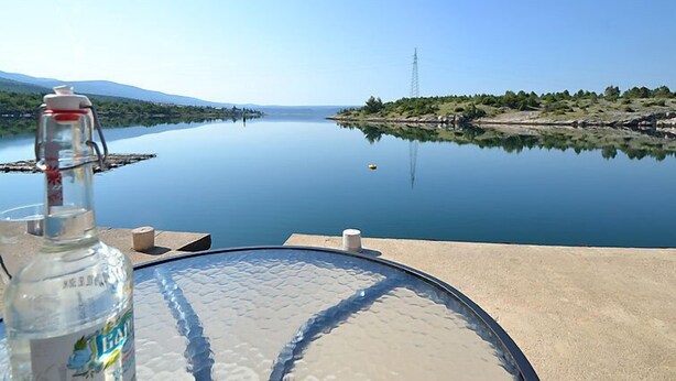 A clear view of a calm lake with a distant power line tower, a bottle of water, and a glass table. - Vacation home Ana by Interhome (Novigrad (Zadar))