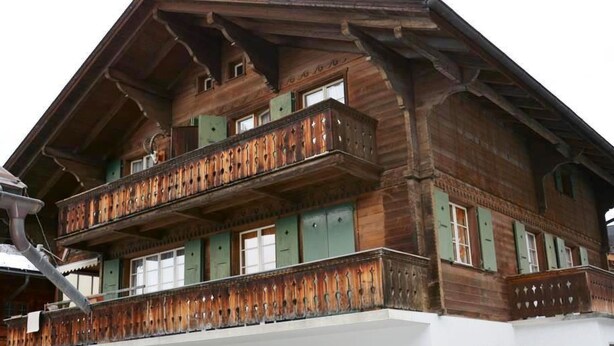 A multi-story wooden building with balconies, green shutters, and a white facade. - Apartment Oehrli by Interhome (Gstaad)