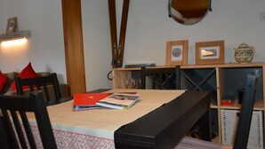 A dining area with a table set for two, wooden chairs, a bench, and a hanging mirror. - Apartment Oehrli by Interhome (Gstaad)