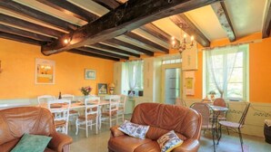 A cozy room with a brown leather sofa, a dining table with chairs, and a chandelier. - Le Jardin de Timothee by Interhome (Montmorillon)
