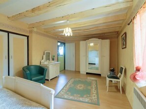 Une pièce avec un plafond en bois, une chaise verte, un bureau blanc, un lit et une petite table avec une chaise.