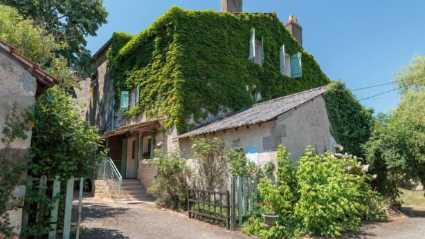 A stone house with a steeply pitched roof, ivy-covered walls, a wooden porch, and a gravel driveway. - Le Jardin de Timothee by Interhome (Montmorillon)