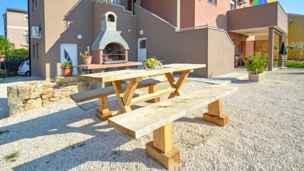 A two-story building with a stone staircase, a wooden bench, and a barbecue area. - Apartment B&B by Interhome (Medulin/Ližnjan)