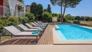 Un espace piscine avec des chaises longues et une terrasse en bois.