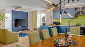 Un salon moderne équipé d’un téléviseur, de sièges et d’un coin repas avec une table mise pour deux personnes.