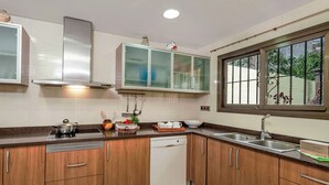 Una cocina moderna con armarios de madera, electrodomésticos de acero inoxidable y un ventanal con vistas a la vegetación.