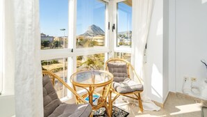 Un balcon avec vue sur la montagne, des meubles en osier et une table en verre.