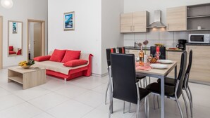 Un appartement moderne comprenant un coin repas, une kitchenette et un salon avec un canapé rouge et une table basse.