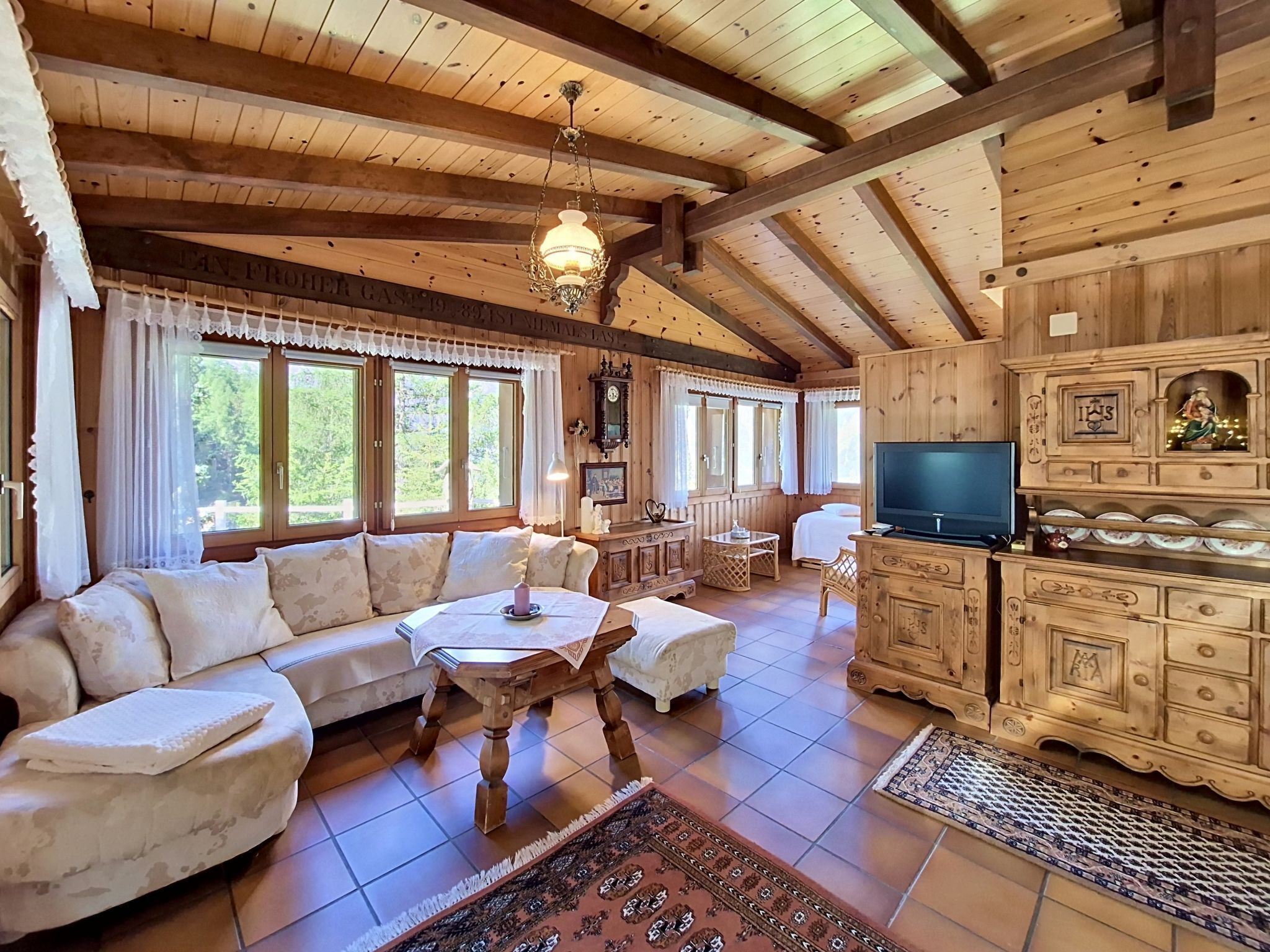 Ein Holzinnenraum mit einer Couch, einem Fernseher und Schränken.