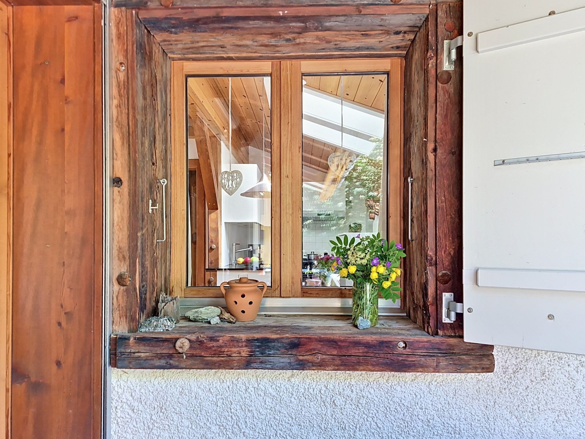 Eine Holztür mit Fensterglas, ein rustikaler Außenbereich und ein kleiner Podeststufenaufgang zu einer weißen Wand.
