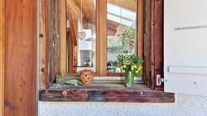 Eine Holztür mit Fensterglas, ein rustikaler Außenbereich und ein kleiner Podeststufenaufgang zu einer weißen Wand.