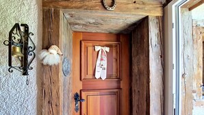 Eine Holztür mit einer verzierten Glocke, einem weißen, flauschigen Ornament und einem Schild mit Text.