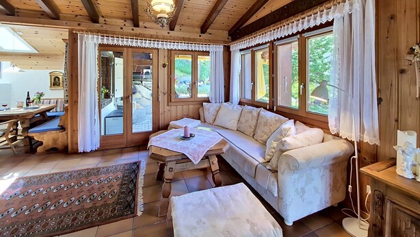 Ein Holzblockbau-Innenraum mit einer Couch, einem Tisch und großen Fenstern.